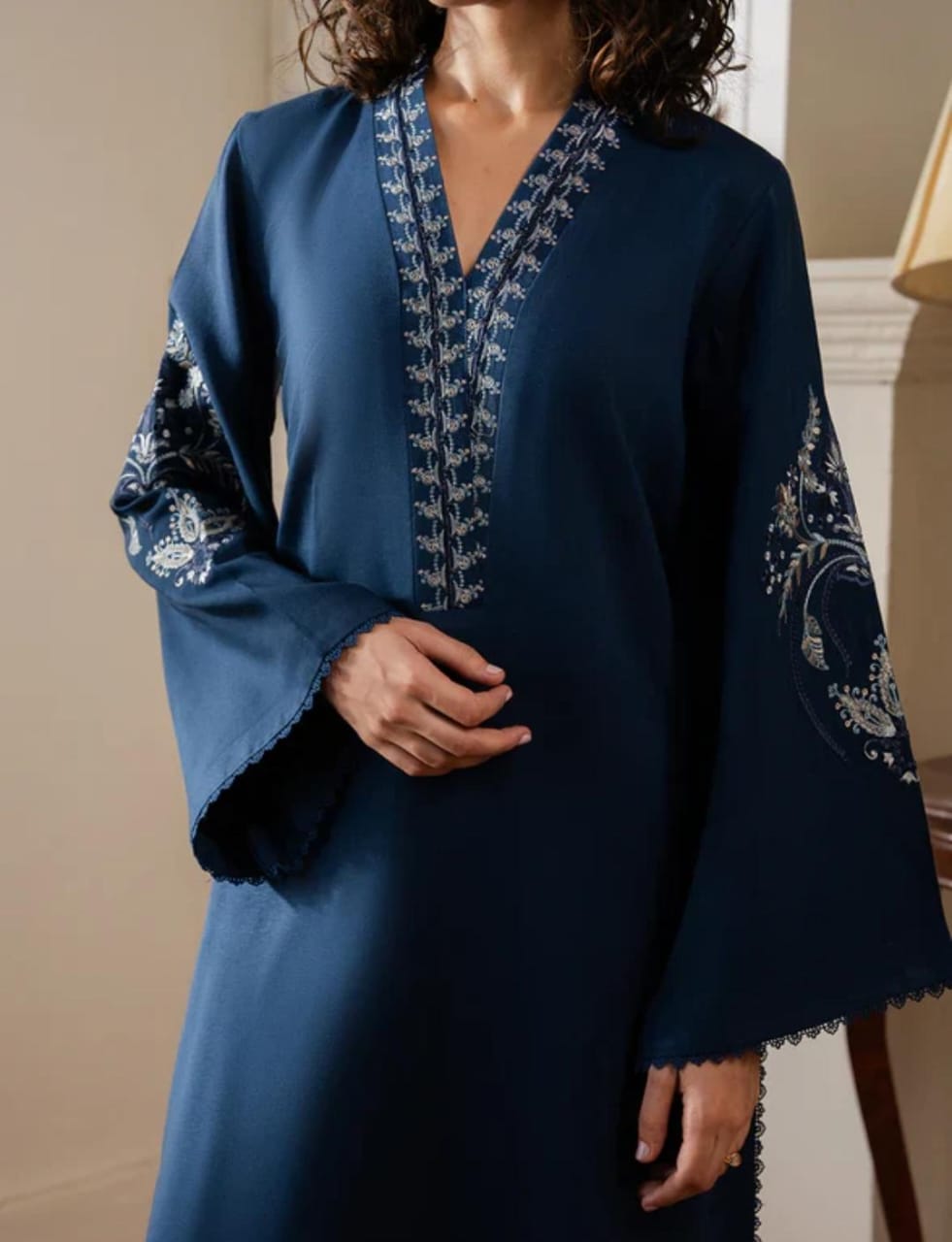Navy blue dress with intricate white embroidery on a neutral background