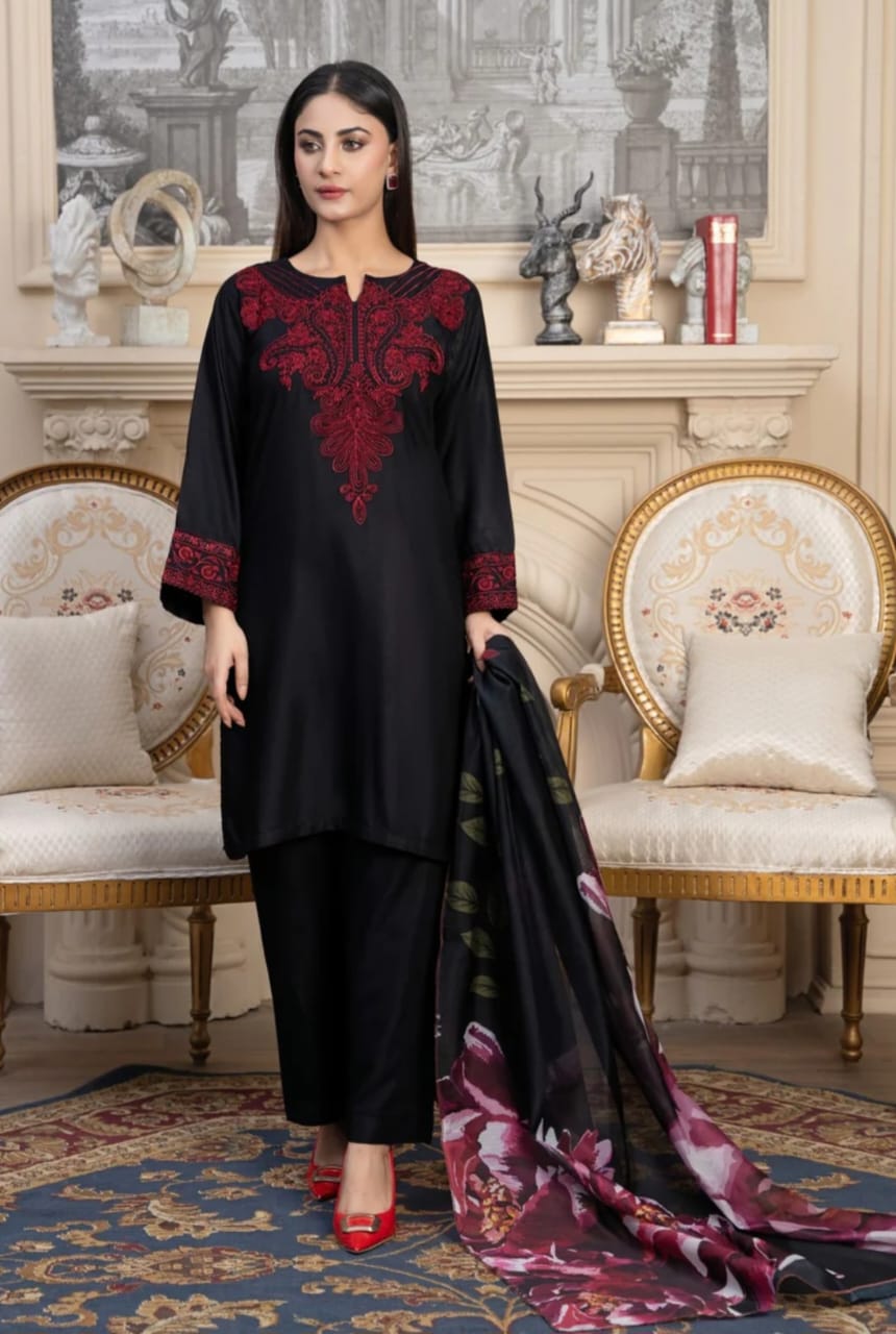 Woman in black outfit with red embroidery holding a floral scarf in an elegant room.