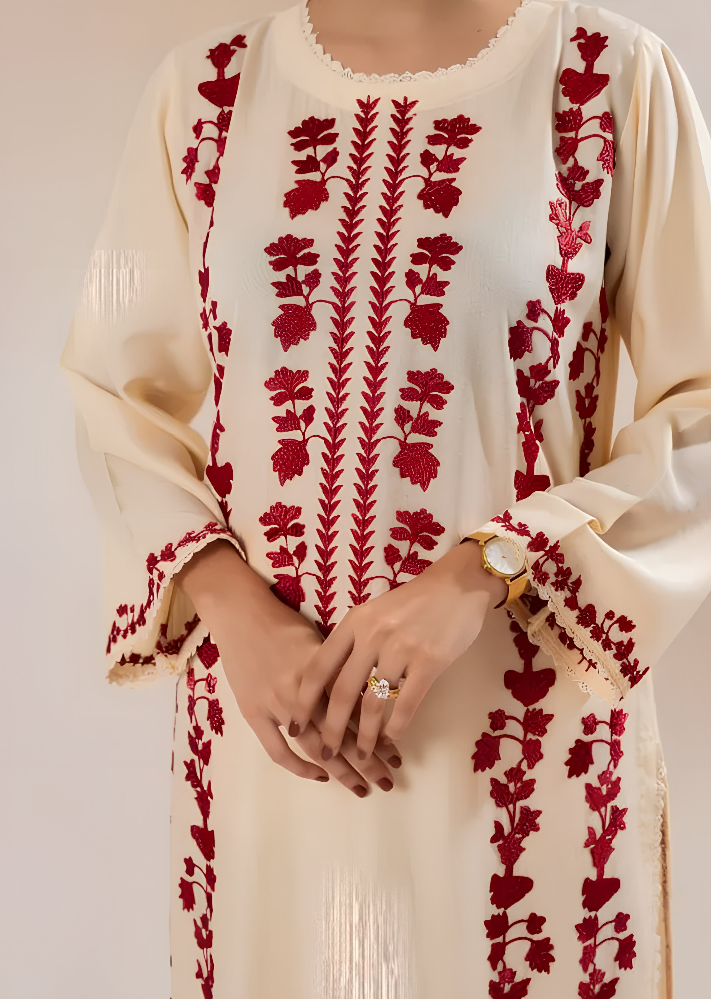 Beige outfit with red floral embroidery on a plain background