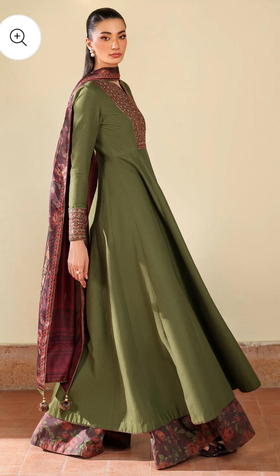 Woman wearing a green and maroon traditional outfit with a matching dupatta on a beige background