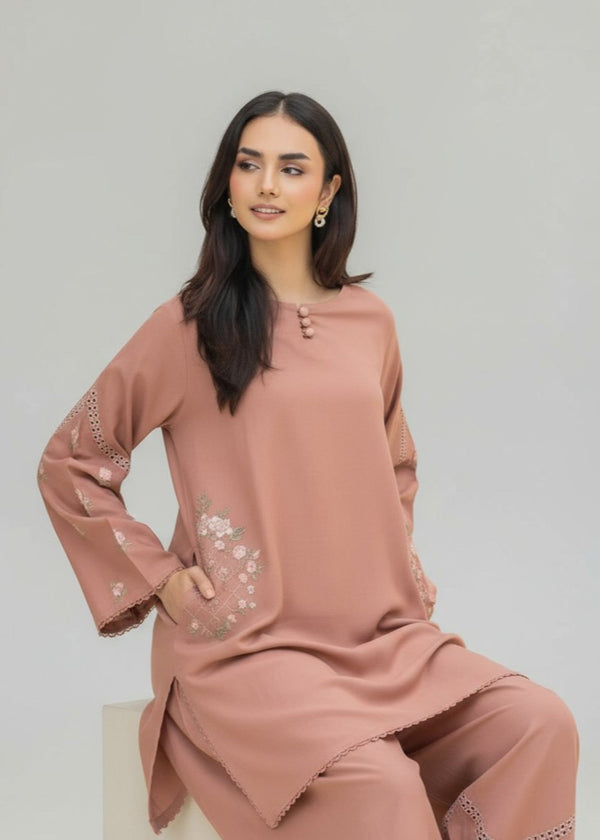 Woman wearing a pink traditional outfit with floral embroidery on a light gray background