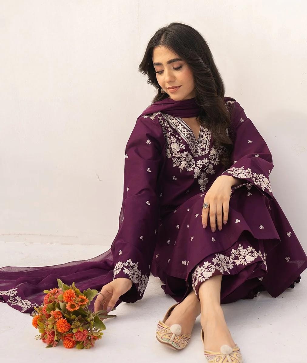 Woman wearing a long purple dress with white patterns on a white background
