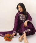 Woman in a purple traditional outfit with floral patterns, sitting on a white background.