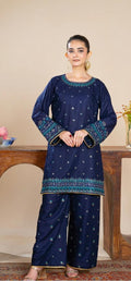 Woman wearing a navy blue traditional outfit with intricate patterns in a room setting.