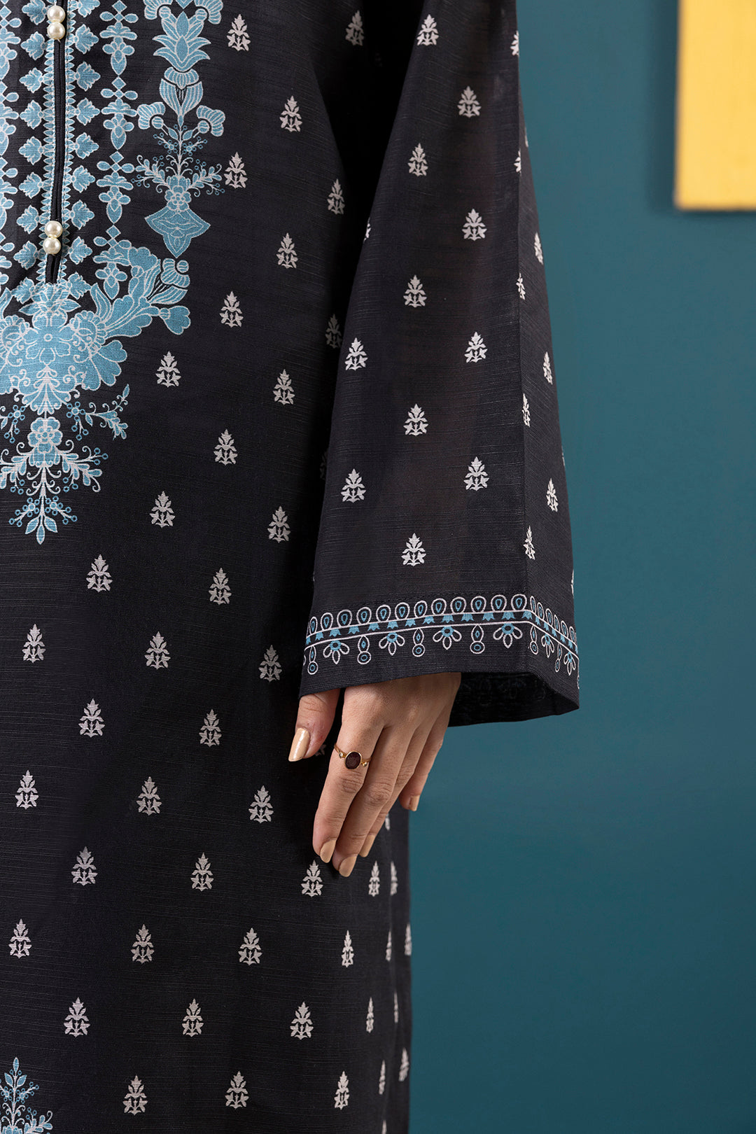 Black dress with white floral patterns against a teal background