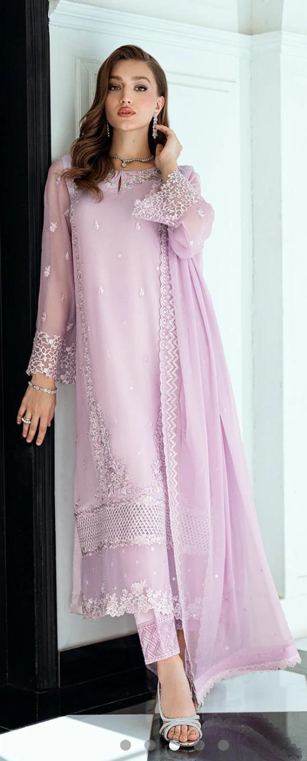 Woman wearing a light pink traditional outfit with lace details in a minimalistic setting.