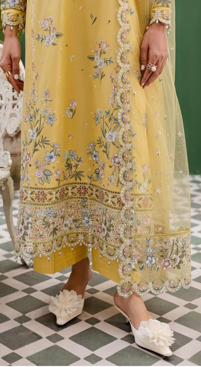 Yellow embroidered traditional outfit with floral patterns on a checkered floor.