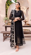 Woman in a black traditional outfit with floral patterns standing in an outdoor setting.