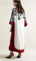 Woman wearing a stylish dress with floral patterns and red accents on a plain background