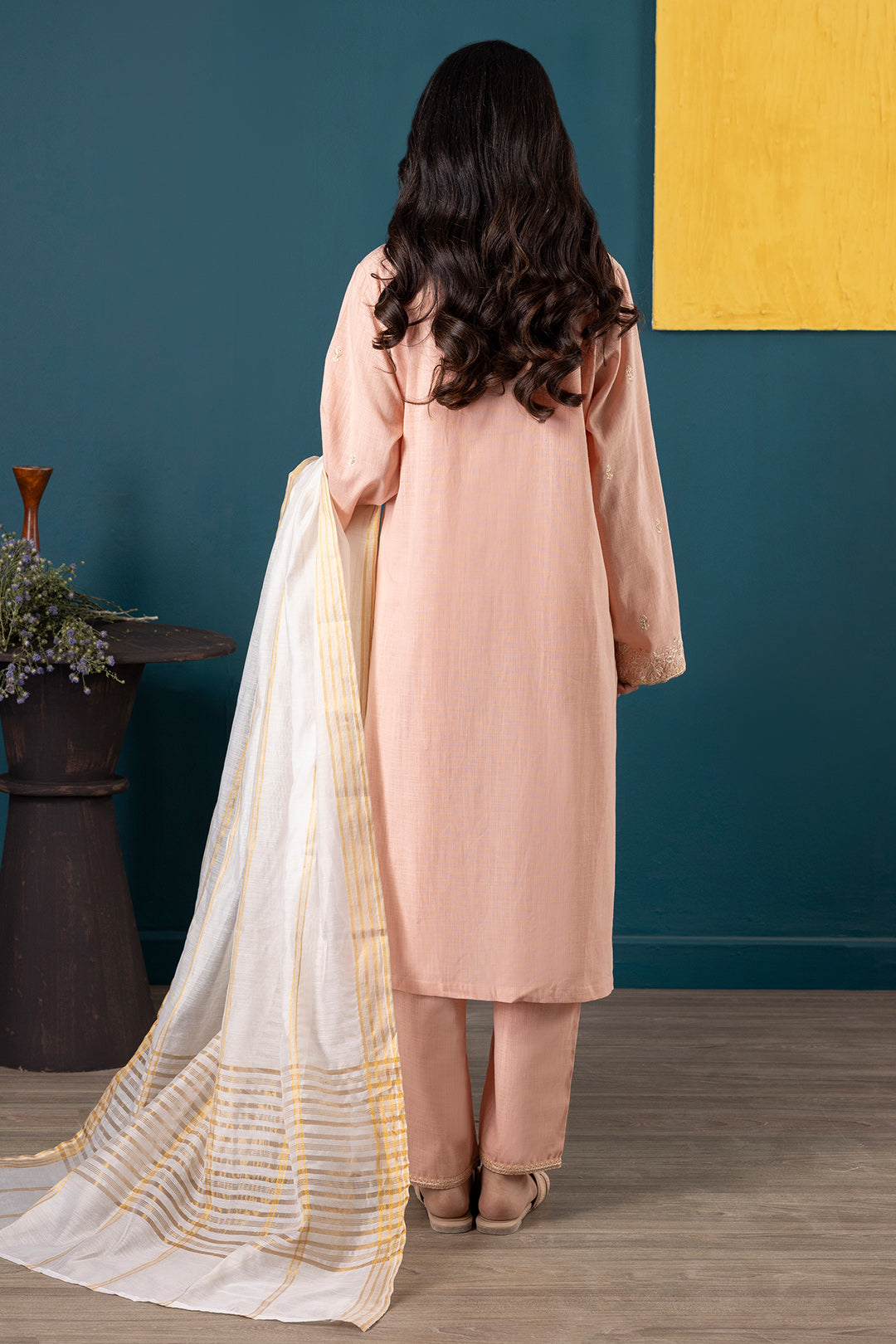 Pink dress with intricate gold embroidery against a blue background