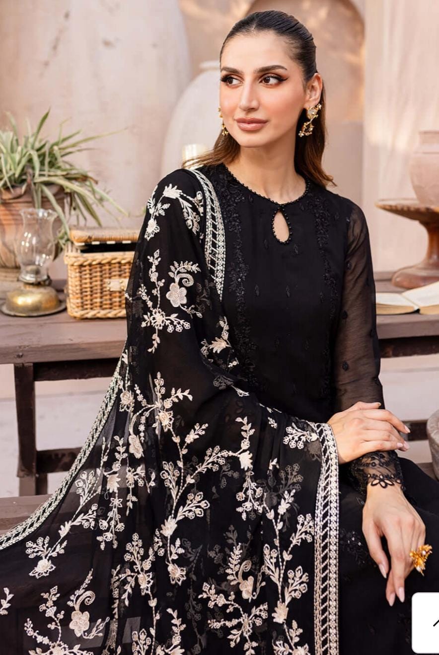 Woman wearing a black outfit with white embroidery sitting in a decorated room.