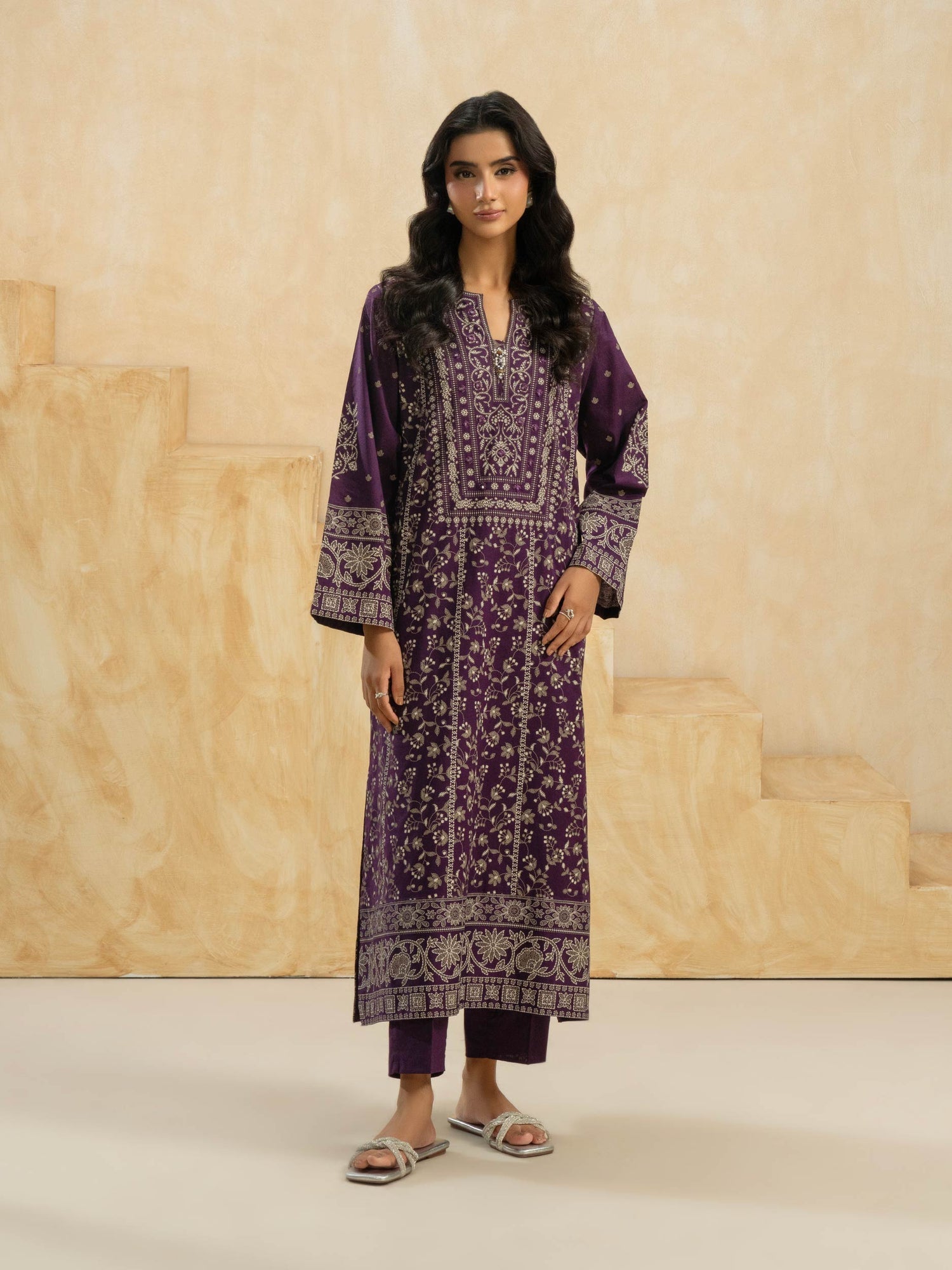 Woman wearing a purple patterned outfit against a beige background