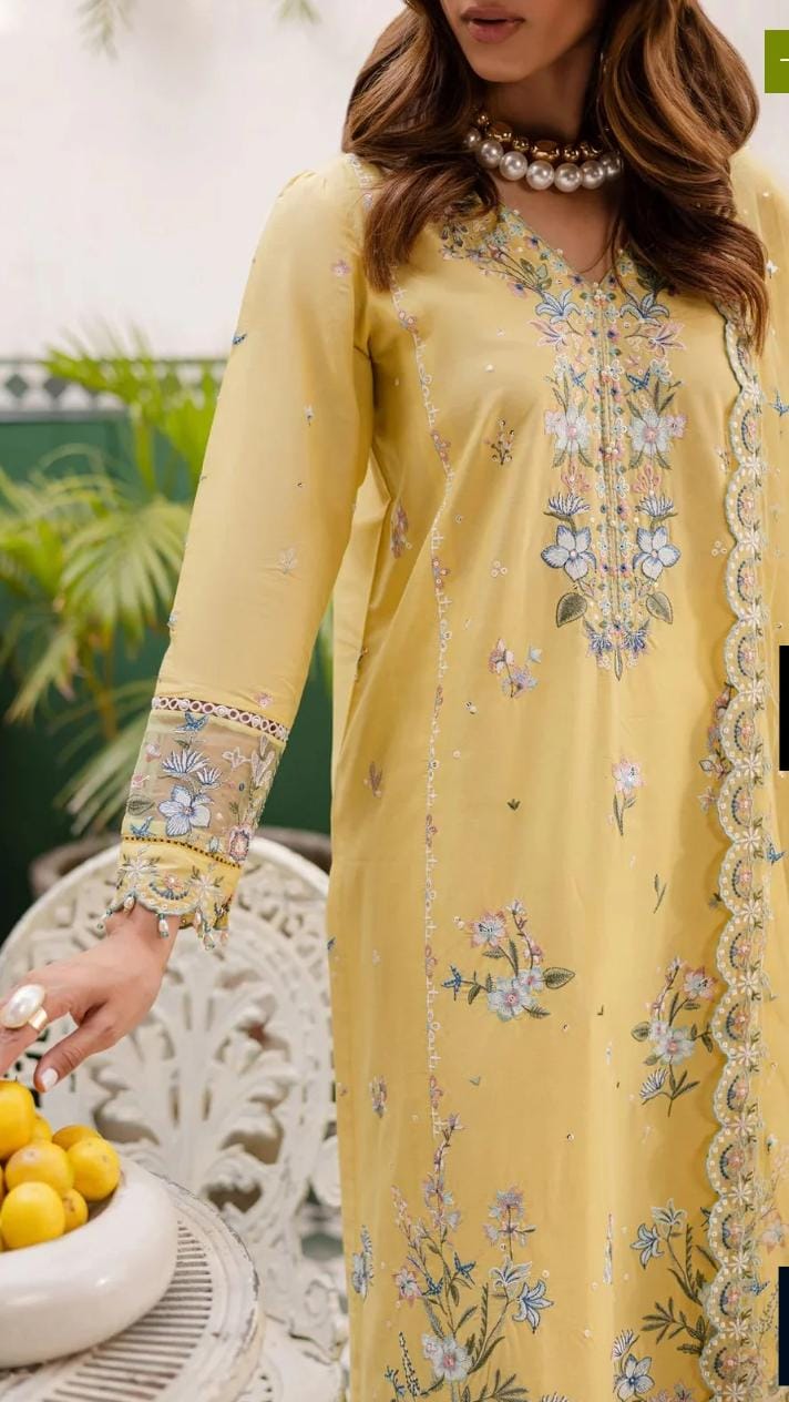 Woman wearing a yellow embroidered dress with floral patterns, sitting outdoors.