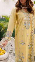 Woman wearing a yellow embroidered dress with floral patterns, sitting outdoors.