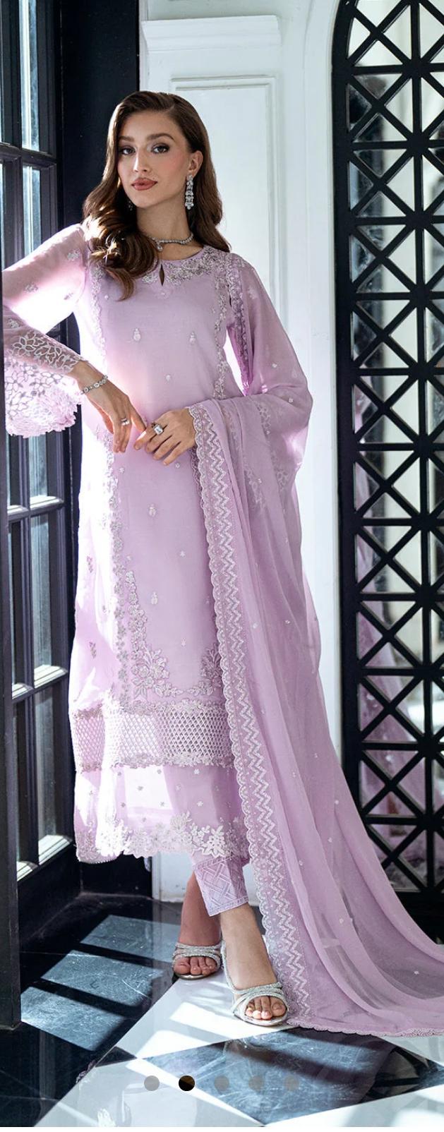 Woman wearing a light pink traditional outfit with a matching dupatta in a stylish interior setting.