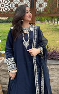 Woman wearing a navy blue traditional outfit with white embroidery in an outdoor setting.