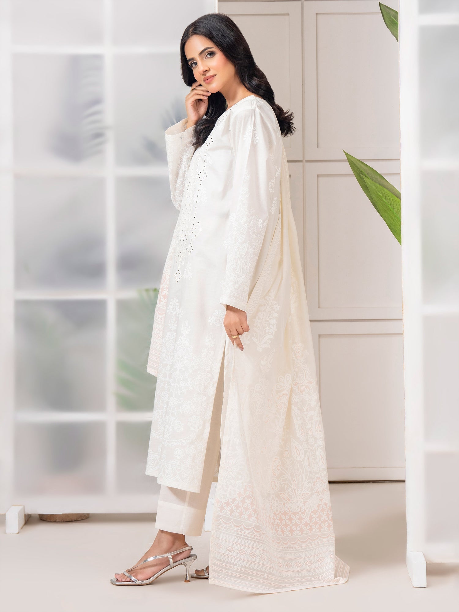 Woman wearing a white traditional outfit in a minimalistic room.