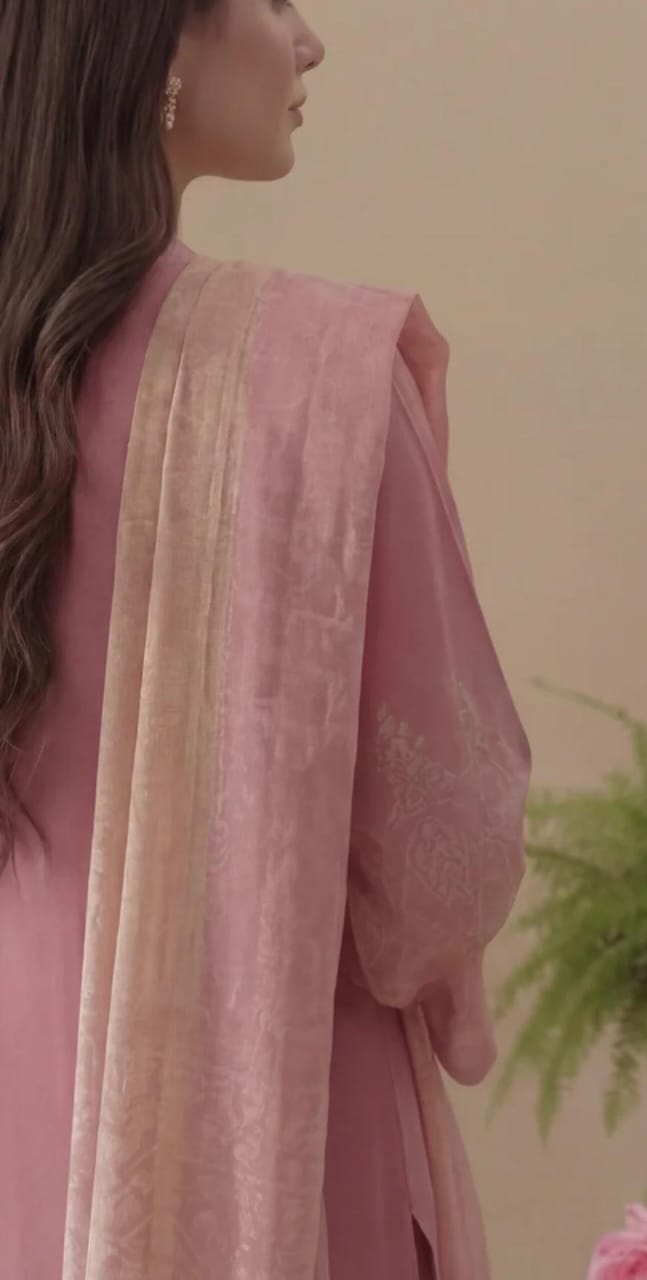 Woman wearing a pink traditional outfit with a beige dupatta against a blurred background