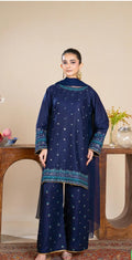 Woman wearing a navy blue traditional outfit with intricate patterns in a room setting.
