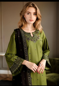 Woman wearing a green and black embroidered traditional outfit indoors.