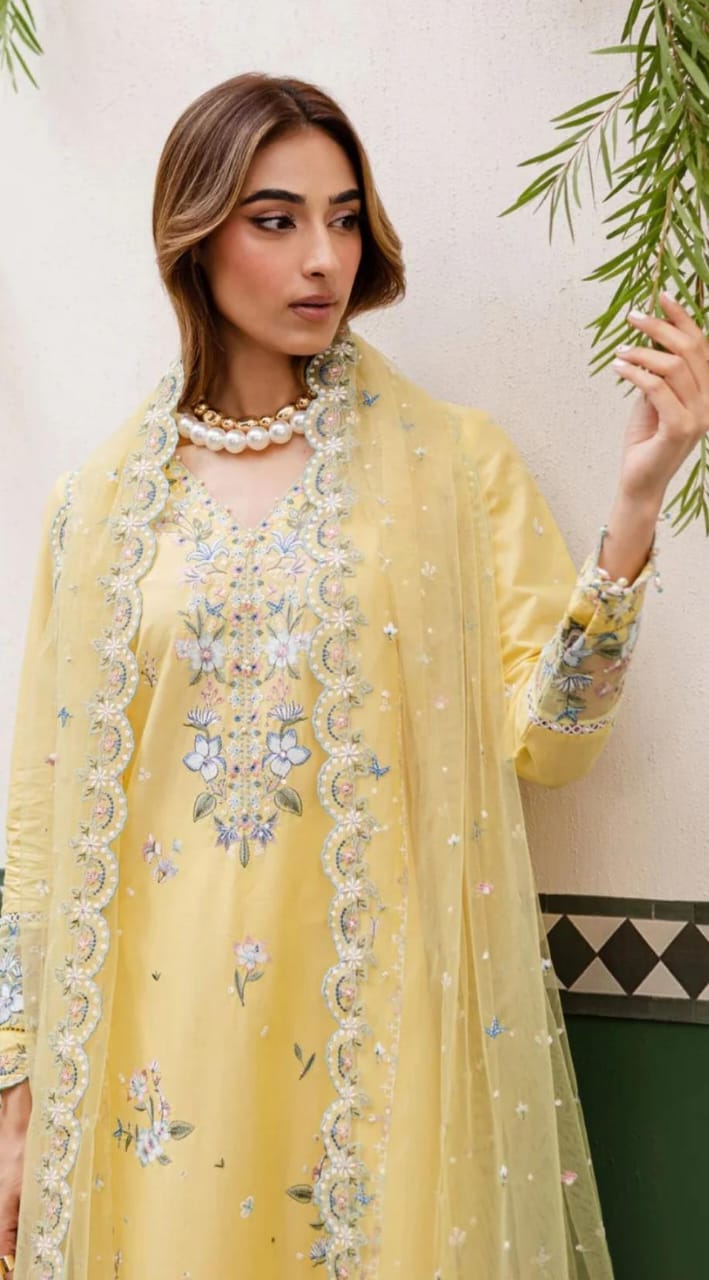 Woman wearing a yellow embroidered traditional outfit with a green background