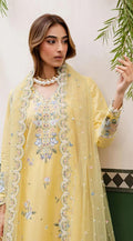 Woman wearing a yellow embroidered outfit with a floral shawl against a light background