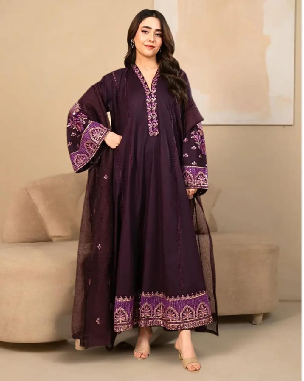 Woman wearing a dark purple embroidered outfit in an indoor setting.
