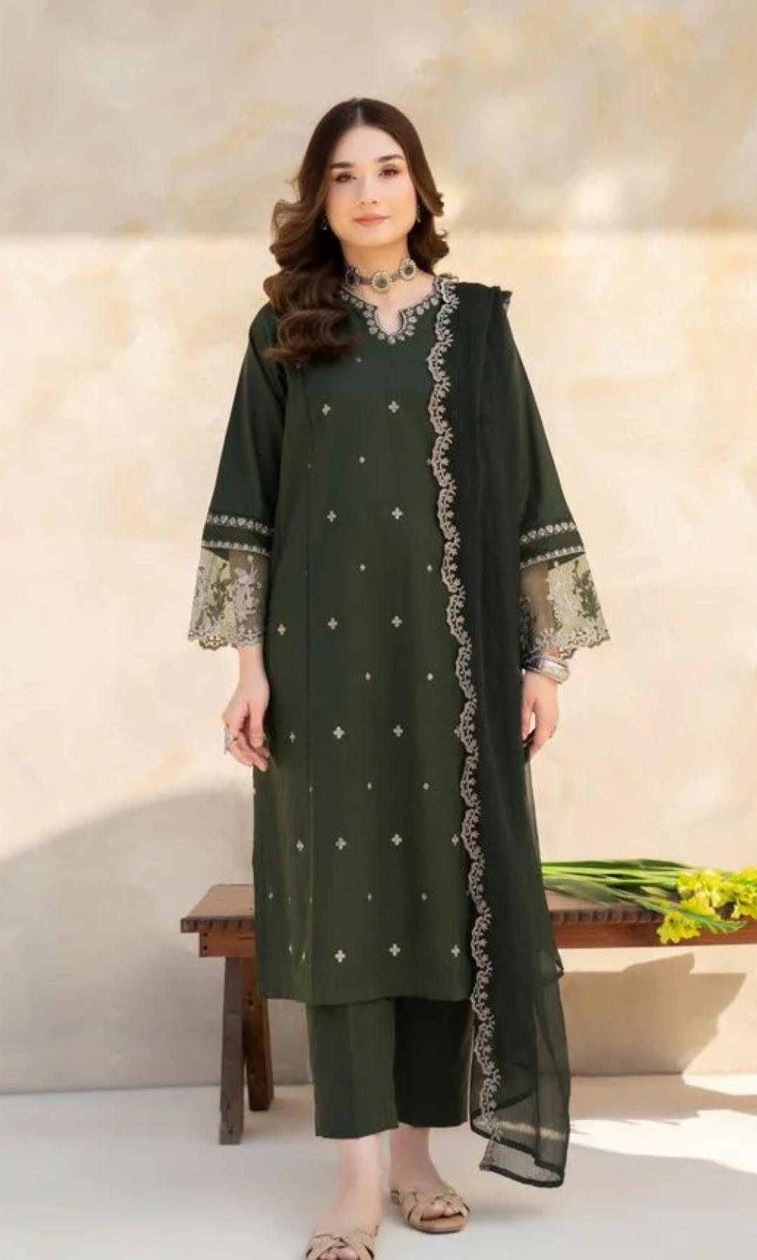 Woman wearing a green embroidered outfit with a neutral background