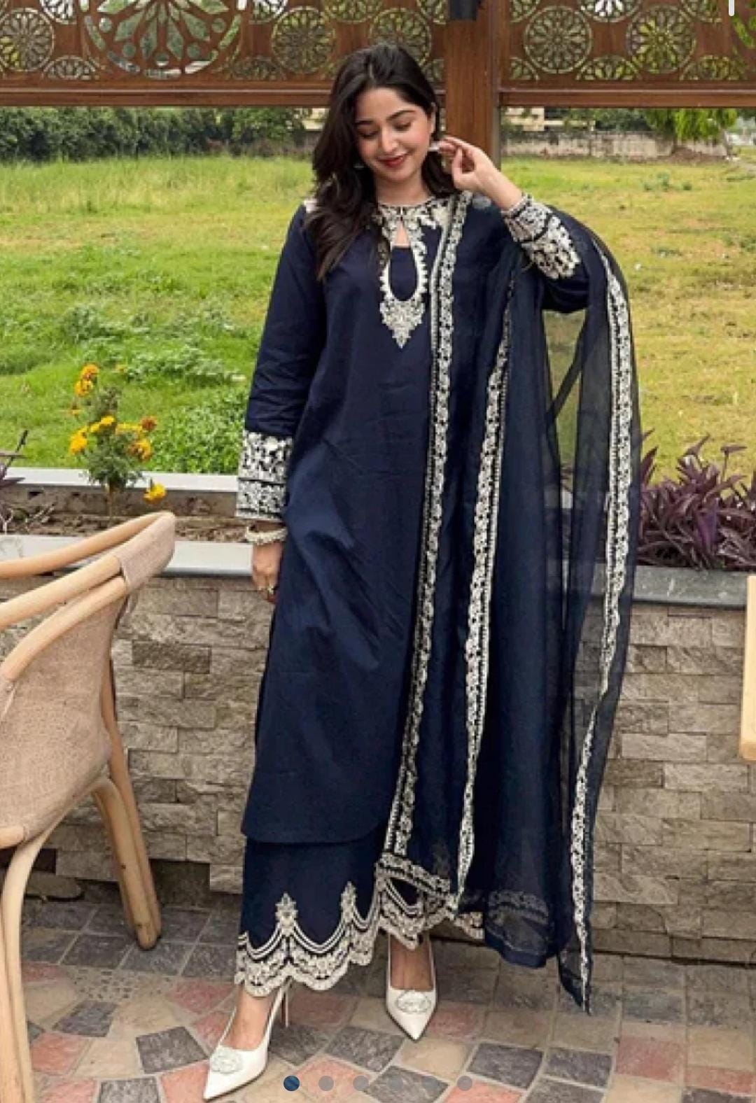 Woman in a navy blue traditional outfit with white embroidery standing outdoors.