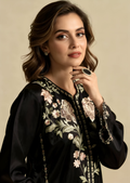 Woman wearing a black outfit with floral embroidery on a beige background