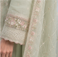 Close-up of a light green embroidered garment with floral patterns.