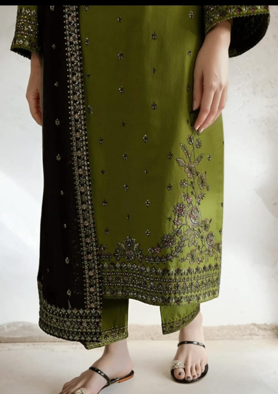 Green and black traditional outfit with floral embroidery on a white background