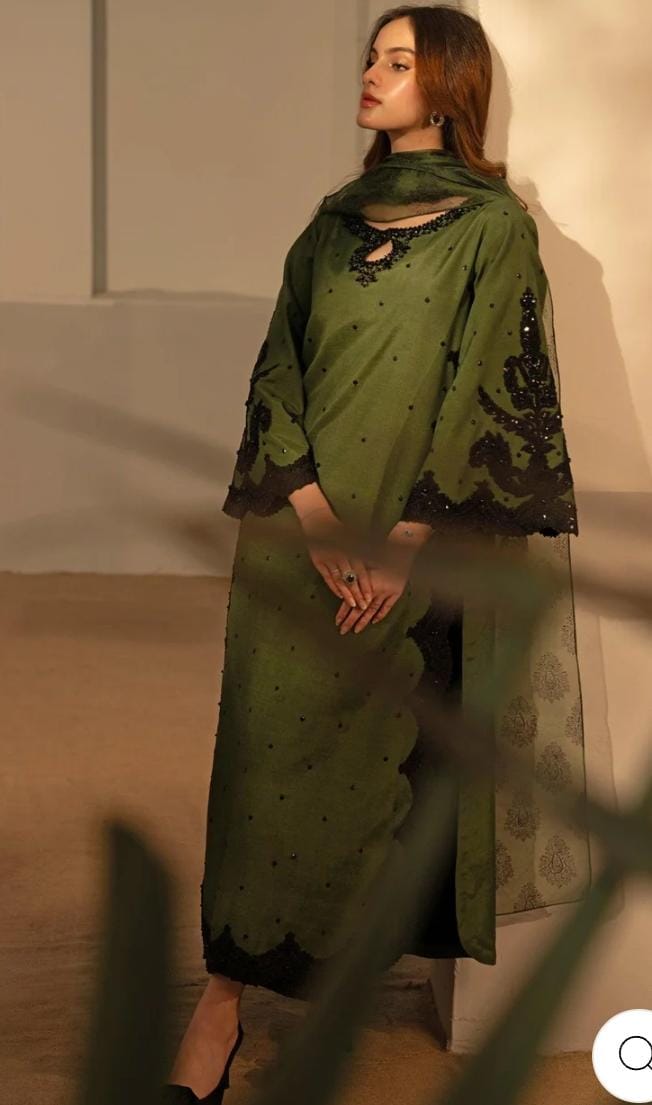 Woman wearing a green traditional outfit with a matching scarf against a neutral background