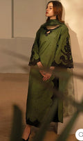 Woman wearing a green traditional outfit with a matching scarf against a neutral background
