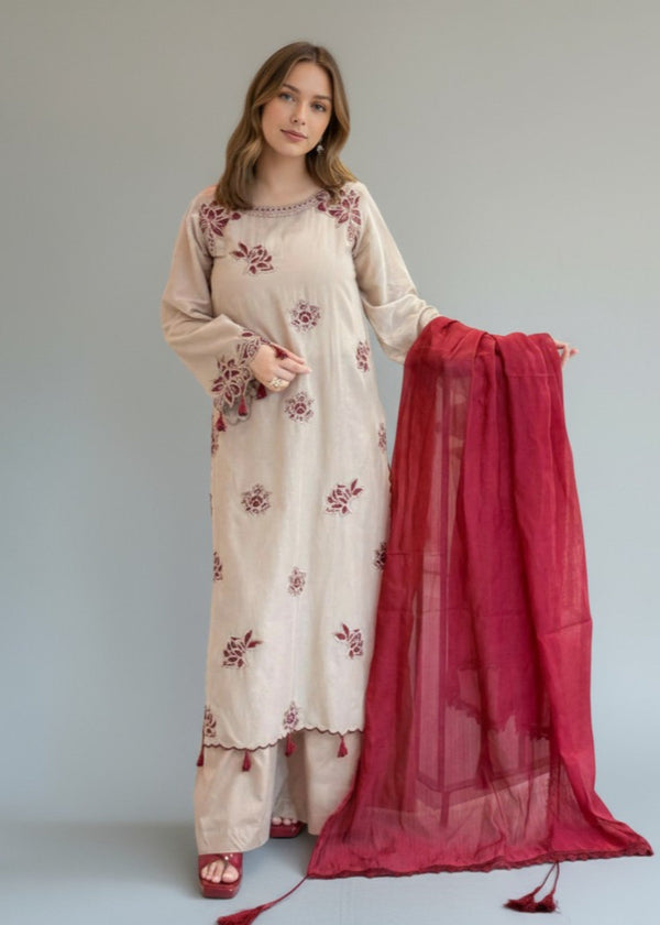 Woman wearing a cream dress with floral embroidery holding a red dupatta against a plain background