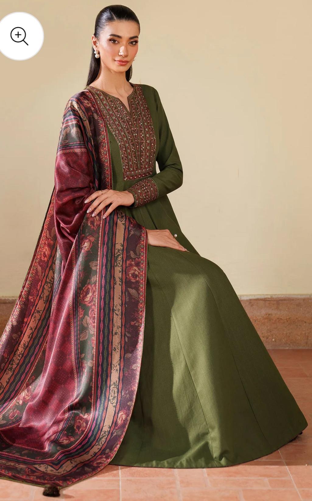 Woman wearing a green and maroon traditional outfit with a long drape.