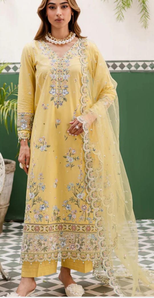 Woman wearing a yellow embroidered traditional outfit with a green background