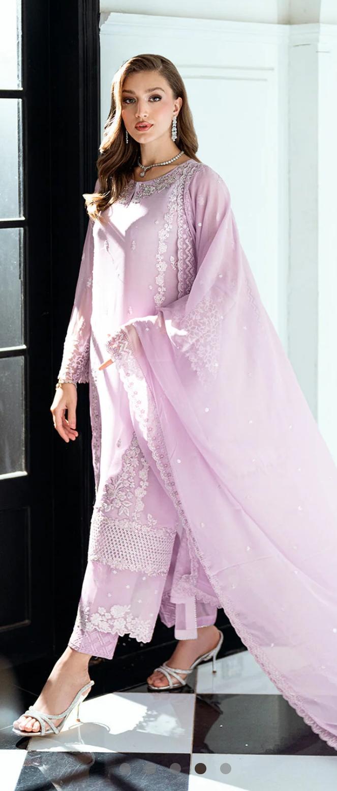 Woman wearing a light pink embroidered traditional outfit with a matching dupatta.
