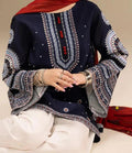 Navy blue embroidered top with white pants on a neutral background