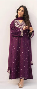 Woman wearing a long purple dress with white patterns on a white background