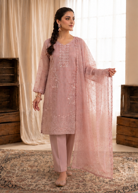 Woman wearing a pink traditional outfit with a matching dupatta in a decorated room.