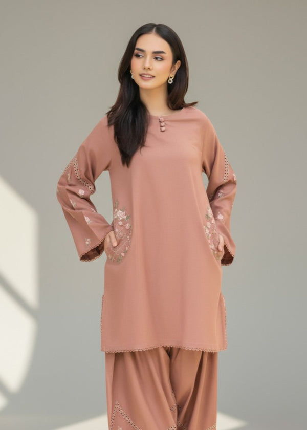 Woman wearing a brown outfit with lace details on a plain background