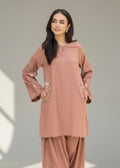 Woman wearing a brown outfit with lace details on a plain background