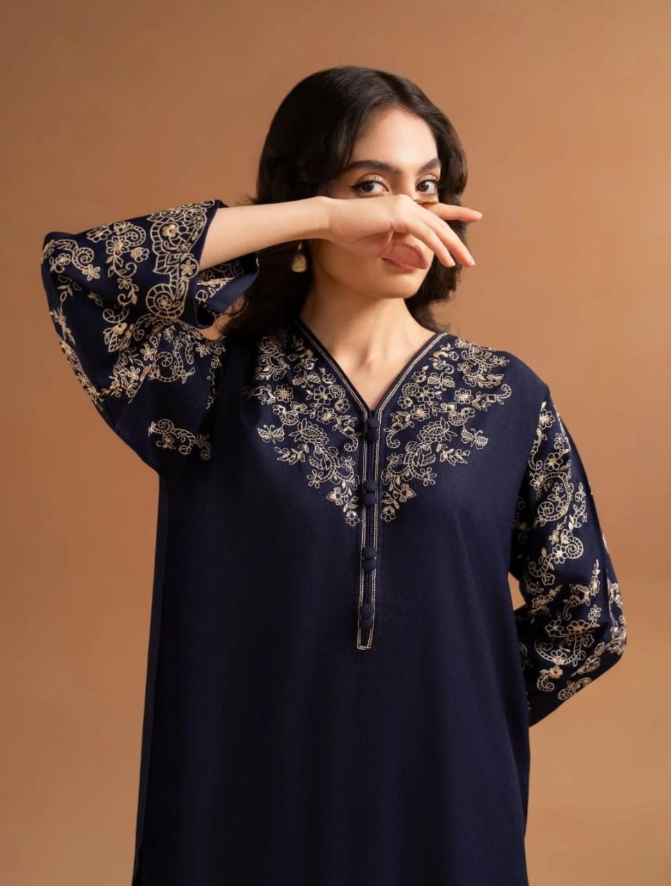 Woman wearing a navy blue dress with floral patterns on a brown background