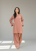 Woman wearing a matching pink kurta and palazzo set on a neutral background